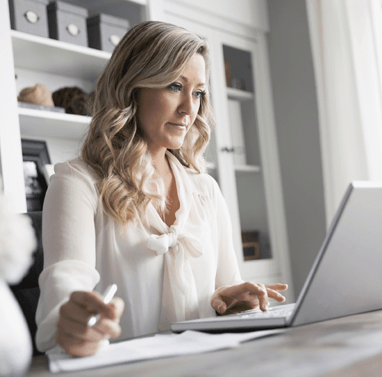 An agent wearing a professional looking white blouse working on a laptop in a clean office setting.
