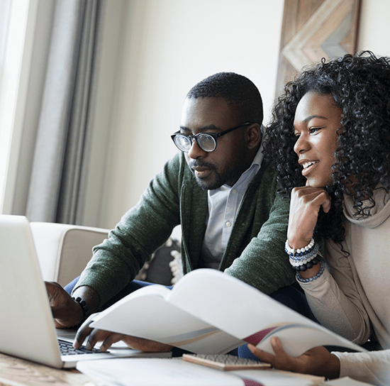 Two Century 21 agents sitting and working together at a desk. The woman appears to be dictating while the man types